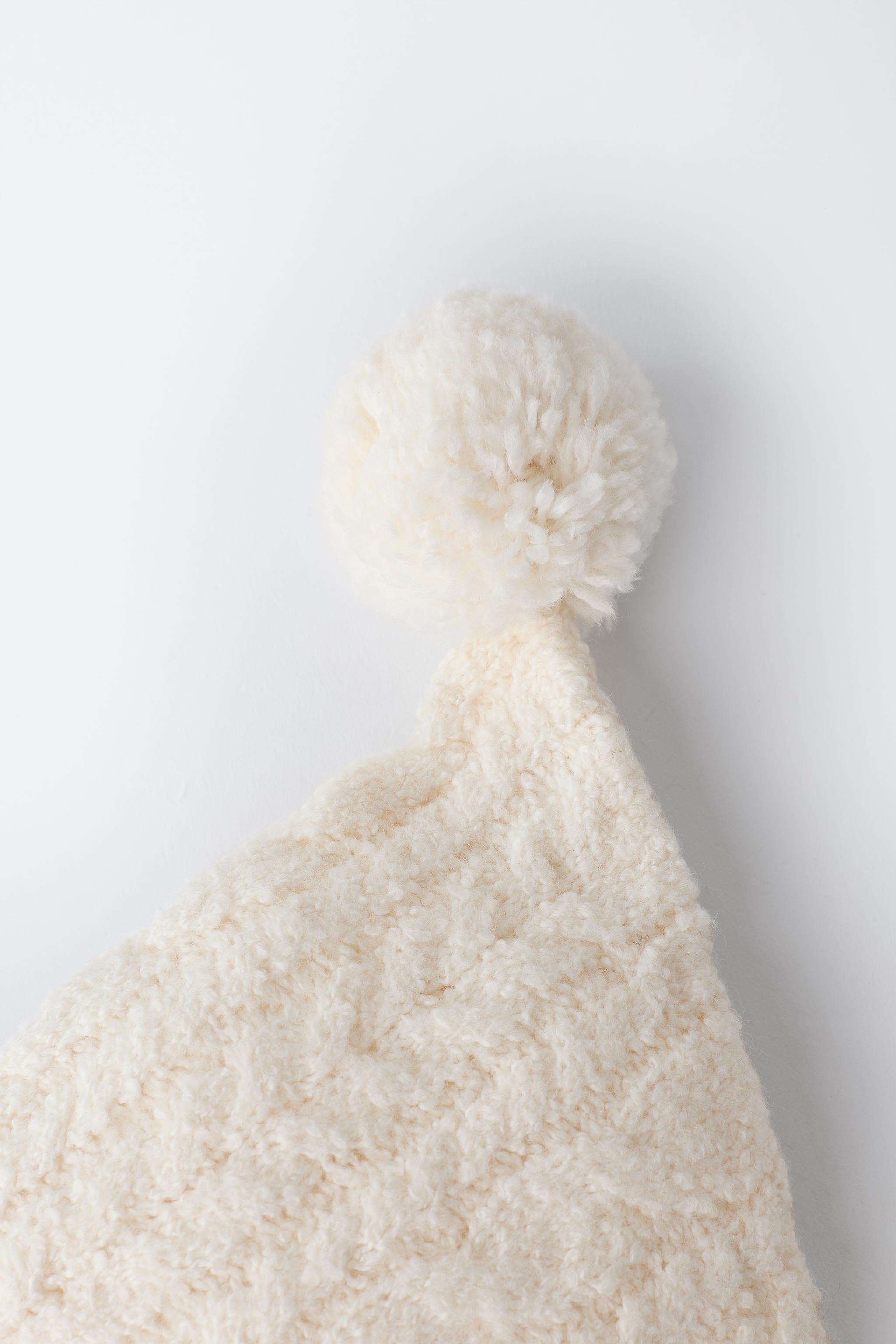 BONNET EN MAILLE À TORSADES ET POMPON